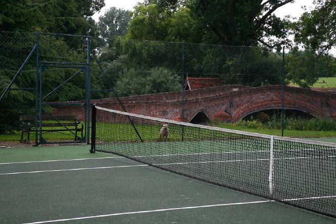 Characterful exterior and gardens of beautiful country house with treehouse, outbuildings, barns, swimming pool and tennis court.
