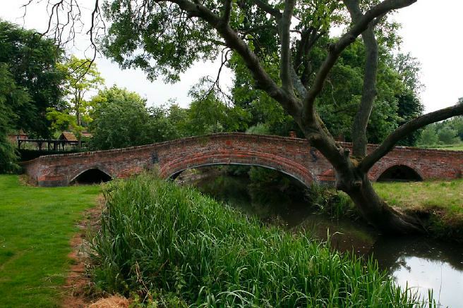 Characterful exterior and gardens of beautiful country house with treehouse, outbuildings, barns, swimming pool and tennis court.