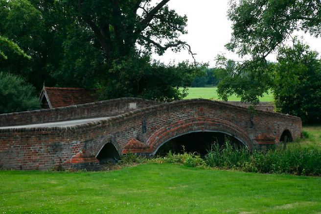Characterful exterior and gardens of beautiful country house with treehouse, outbuildings, barns, swimming pool and tennis court.