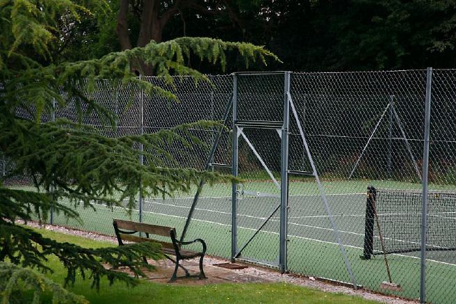 Characterful exterior and gardens of beautiful country house with treehouse, outbuildings, barns, swimming pool and tennis court.