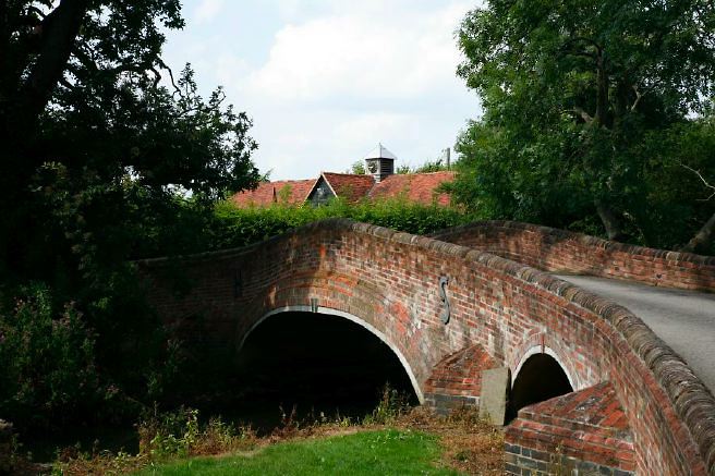 Characterful exterior and gardens of beautiful country house with treehouse, outbuildings, barns, swimming pool and tennis court.