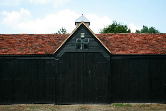 Characterful exterior and gardens of beautiful country house with treehouse, outbuildings, barns, swimming pool and tennis court.