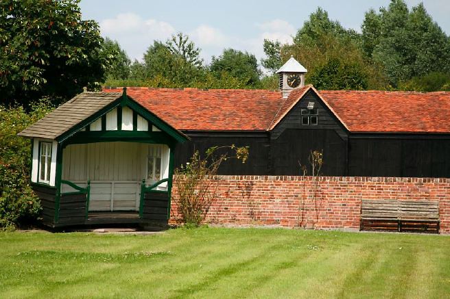 Characterful exterior and gardens of beautiful country house with treehouse, outbuildings, barns, swimming pool and tennis court.