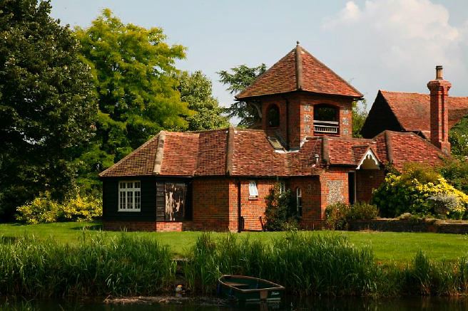 Characterful exterior and gardens of beautiful country house with treehouse, outbuildings, barns, swimming pool and tennis court.
