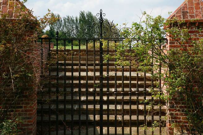 Characterful exterior and gardens of beautiful country house with treehouse, outbuildings, barns, swimming pool and tennis court.