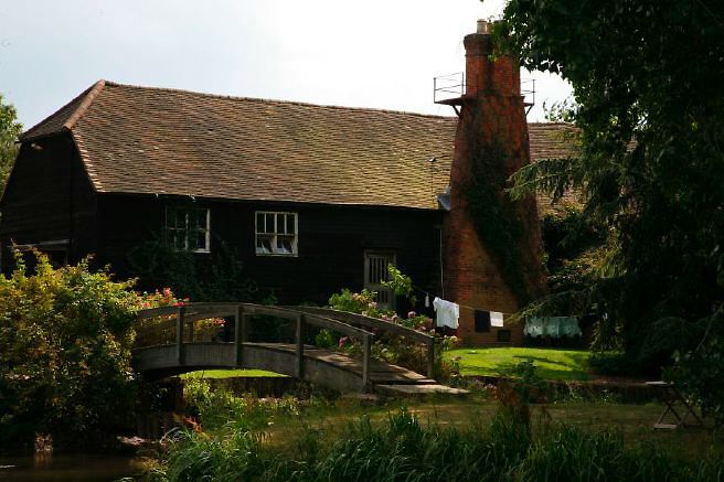Characterful exterior and gardens of beautiful country house with treehouse, outbuildings, barns, swimming pool and tennis court.