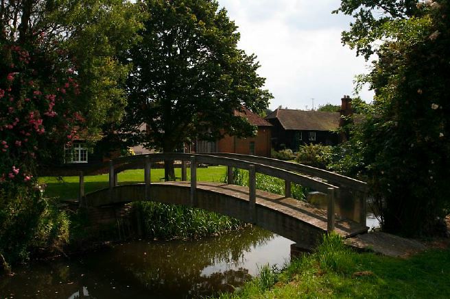 Characterful exterior and gardens of beautiful country house with treehouse, outbuildings, barns, swimming pool and tennis court.