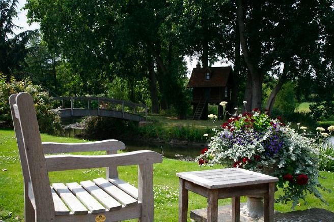 Characterful exterior and gardens of beautiful country house with treehouse, outbuildings, barns, swimming pool and tennis court.
