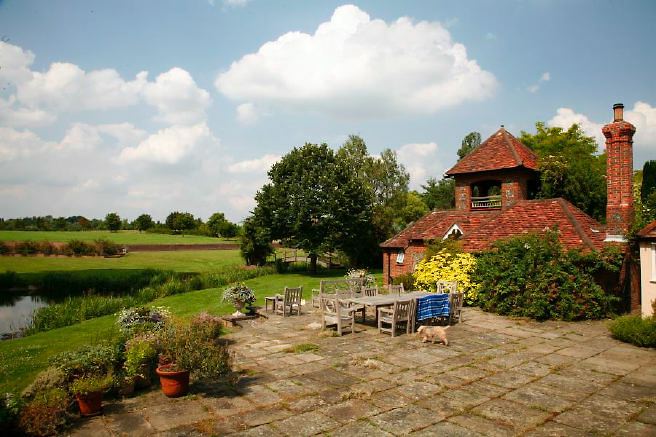Characterful exterior and gardens of beautiful country house with treehouse, outbuildings, barns, swimming pool and tennis court.