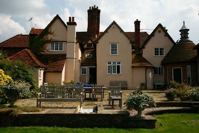 Characterful exterior and gardens of beautiful country house with treehouse, outbuildings, barns, swimming pool and tennis court.