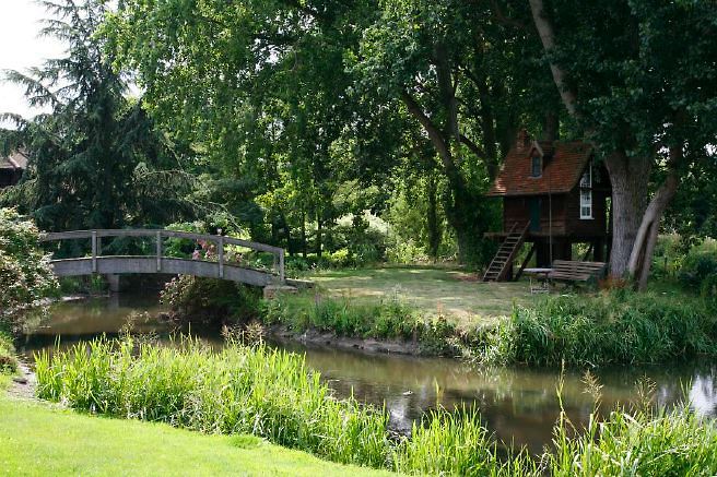 Characterful exterior and gardens of beautiful country house with treehouse, outbuildings, barns, swimming pool and tennis court.