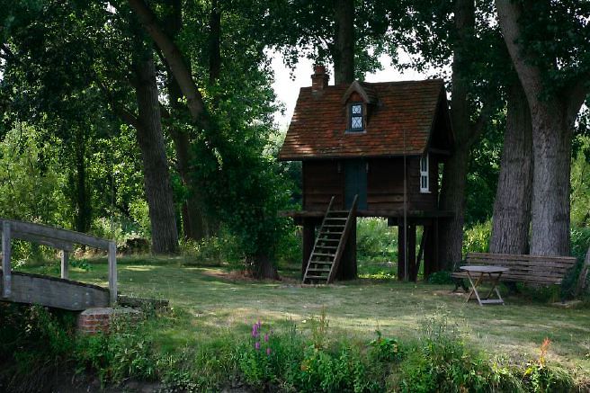 Characterful exterior and gardens of beautiful country house with treehouse, outbuildings, barns, swimming pool and tennis court.