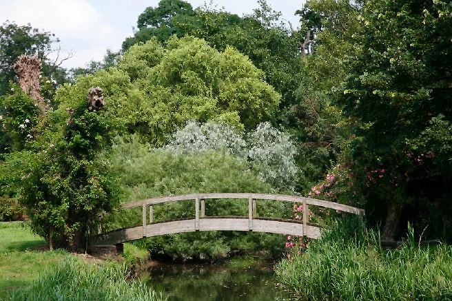 Characterful exterior and gardens of beautiful country house with treehouse, outbuildings, barns, swimming pool and tennis court.
