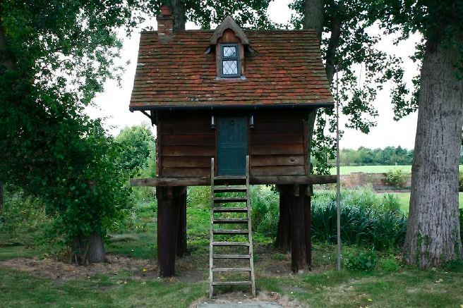 Characterful exterior and gardens of beautiful country house with treehouse, outbuildings, barns, swimming pool and tennis court.