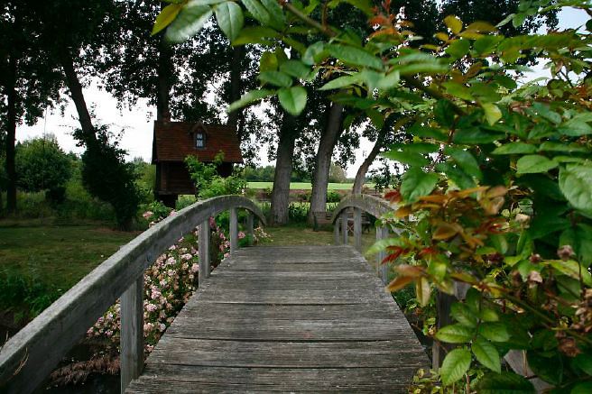Characterful exterior and gardens of beautiful country house with treehouse, outbuildings, barns, swimming pool and tennis court.