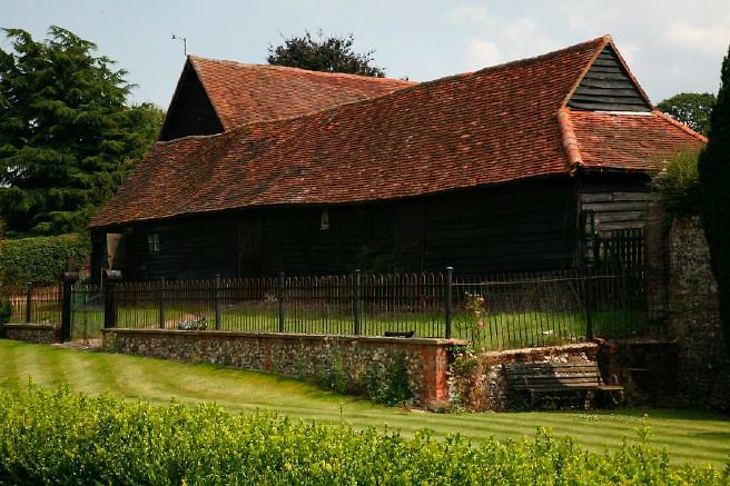 Characterful exterior and gardens of beautiful country house with treehouse, outbuildings, barns, swimming pool and tennis court.