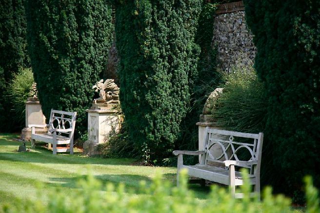 Characterful exterior and gardens of beautiful country house with treehouse, outbuildings, barns, swimming pool and tennis court.
