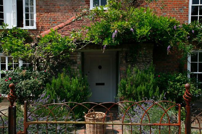 Characterful exterior and gardens of beautiful country house with treehouse, outbuildings, barns, swimming pool and tennis court.