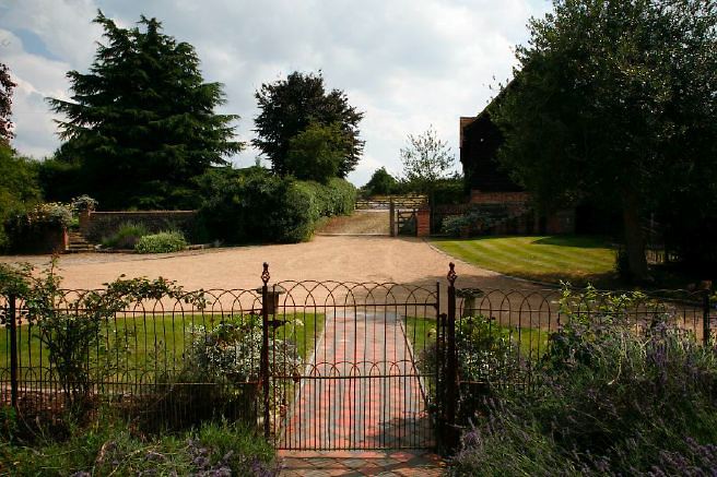 Characterful exterior and gardens of beautiful country house with treehouse, outbuildings, barns, swimming pool and tennis court.