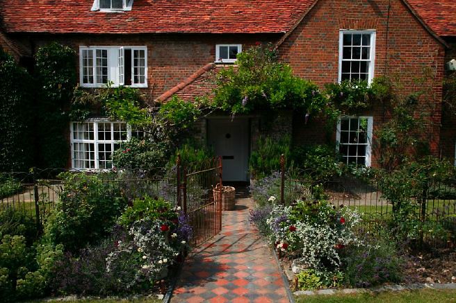 Characterful exterior and gardens of beautiful country house with treehouse, outbuildings, barns, swimming pool and tennis court.