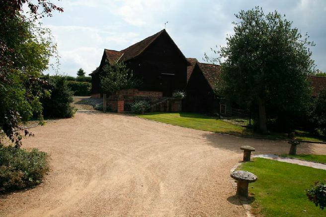 Characterful exterior and gardens of beautiful country house with treehouse, outbuildings, barns, swimming pool and tennis court.