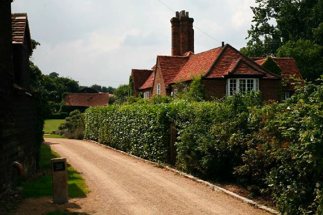 Characterful exterior and gardens of beautiful country house with treehouse, outbuildings, barns, swimming pool and tennis court.