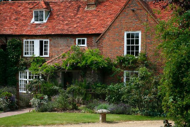 Characterful exterior and gardens of beautiful country house with treehouse, outbuildings, barns, swimming pool and tennis court.