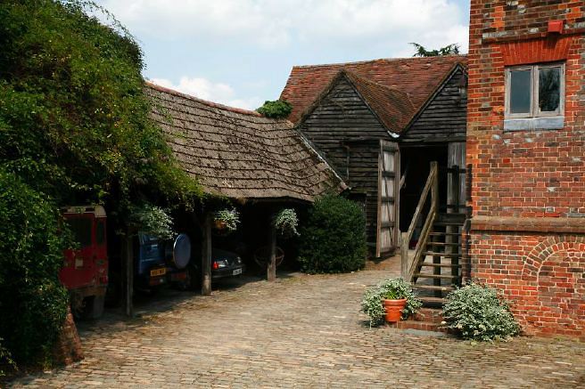 Characterful exterior and gardens of beautiful country house with treehouse, outbuildings, barns, swimming pool and tennis court.