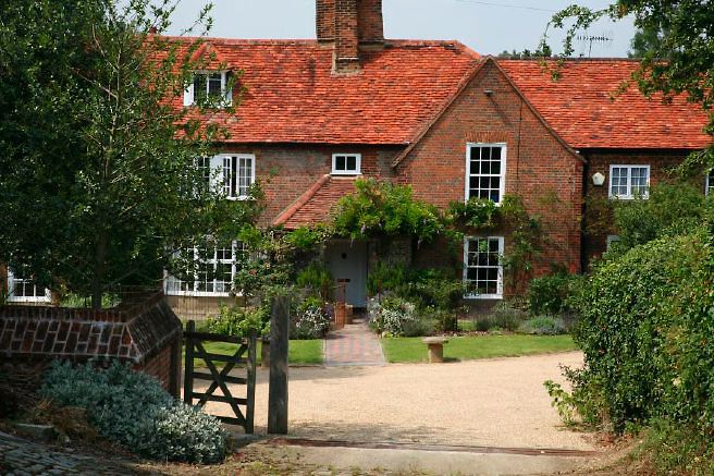 Characterful exterior and gardens of beautiful country house with treehouse, outbuildings, barns, swimming pool and tennis court.