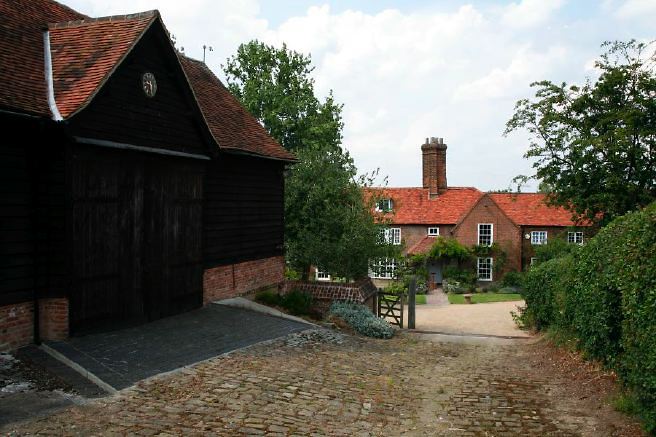 Characterful exterior and gardens of beautiful country house with treehouse, outbuildings, barns, swimming pool and tennis court.