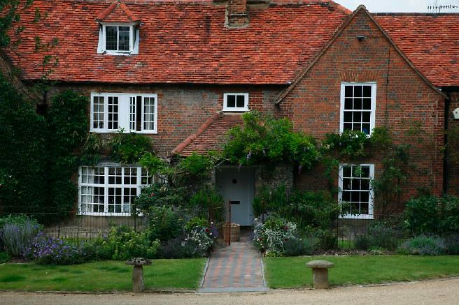 Characterful exterior and gardens of beautiful country house with treehouse, outbuildings, barns, swimming pool and tennis court.