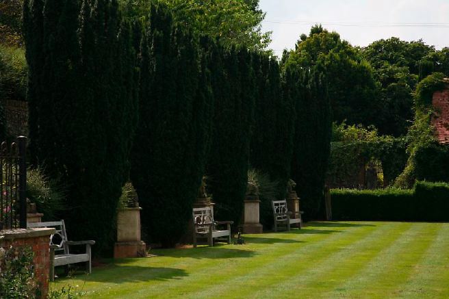 Characterful exterior and gardens of beautiful country house with treehouse, outbuildings, barns, swimming pool and tennis court.
