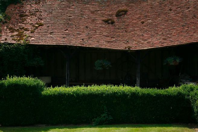 Characterful exterior and gardens of beautiful country house with treehouse, outbuildings, barns, swimming pool and tennis court.