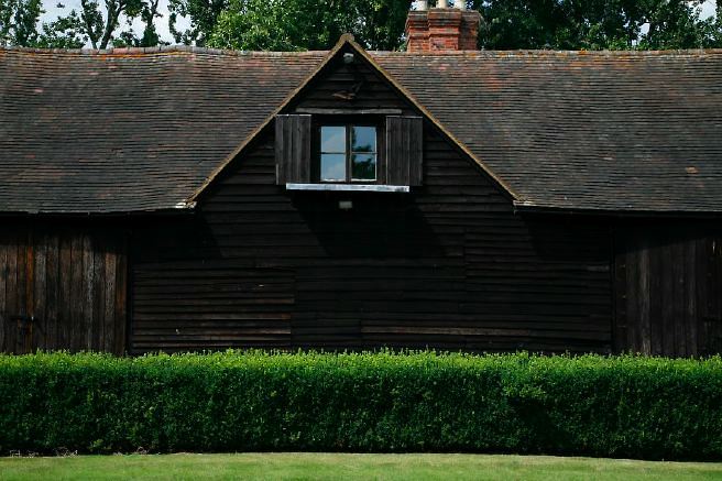 Characterful exterior and gardens of beautiful country house with treehouse, outbuildings, barns, swimming pool and tennis court.
