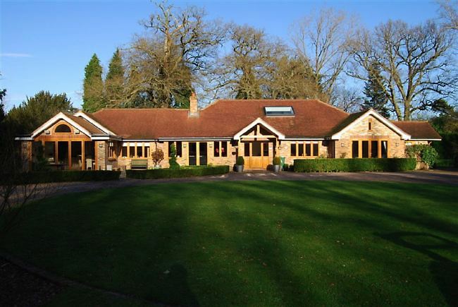 Country garden in woodland setting with a pond and children's play area.