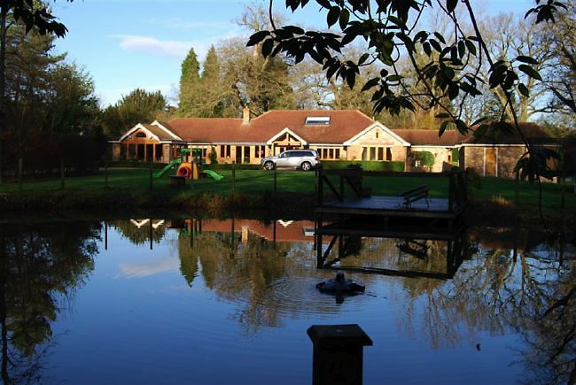Country garden in woodland setting with a pond and children's play area.