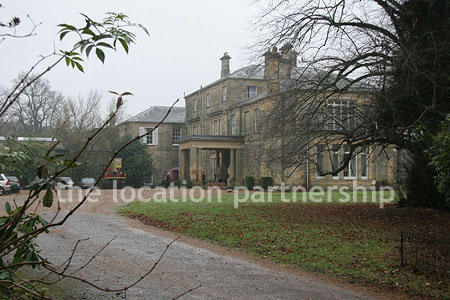 Gravel driveway leading to a pillared portico at the entrance to a large Country House