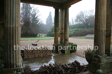 Gravel driveway leading to a pillared portico at the entrance to a large Country House