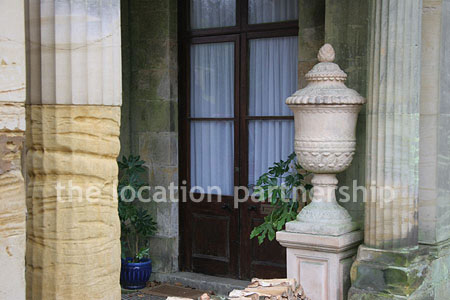 Gravel driveway leading to a pillared portico at the entrance to a large Country House