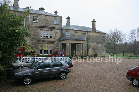 Gravel driveway leading to a pillared portico at the entrance to a large Country House