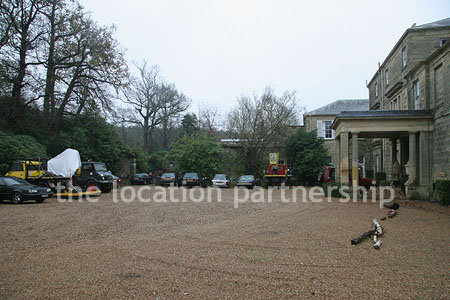 Gravel driveway leading to a pillared portico at the entrance to a large Country House