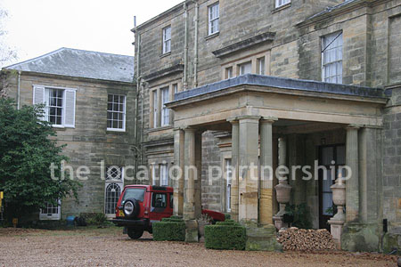 Gravel driveway leading to a pillared portico at the entrance to a large Country House