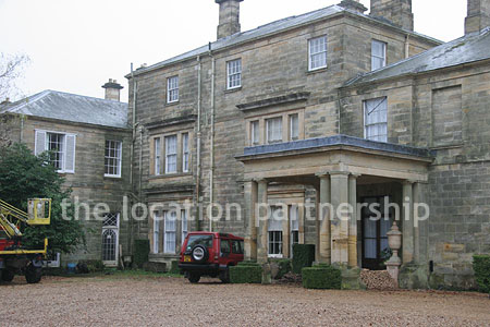 Gravel driveway leading to a pillared portico at the entrance to a large Country House