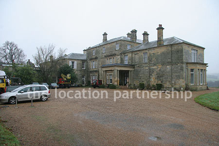 Gravel driveway leading to a pillared portico at the entrance to a large Country House