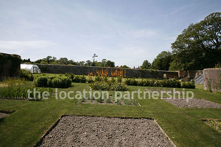 Walled flower and vegetable garden with variety of greenhouses