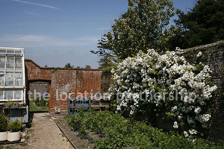 Walled flower and vegetable garden with variety of greenhouses