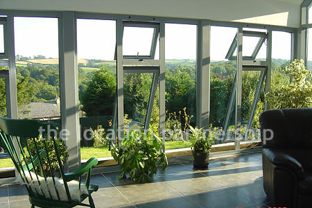 Double height sitting room/ conservatory with full length windows and overhead skylight.