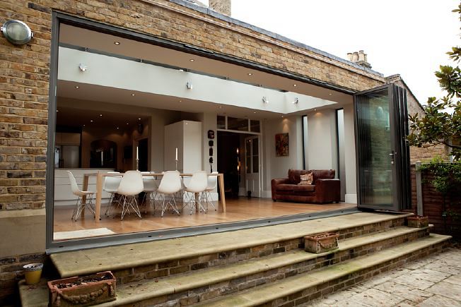 A large Victorian house with open plan ground floor and large white modern Kitchen/ Dining area with floor to ceiling windows and double length sitting room.