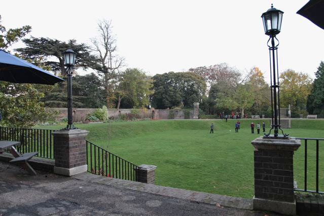 Beautiful historic house garden with an old stone bridge, walled gardens, manicured hedges, a circular pond and an ornate fountain