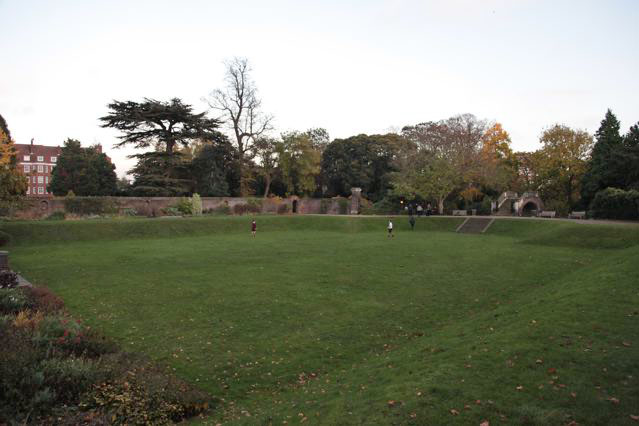 Beautiful historic house garden with an old stone bridge, walled gardens, manicured hedges, a circular pond and an ornate fountain